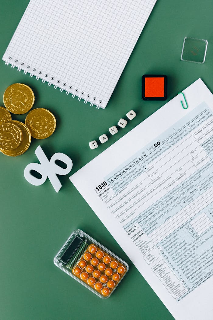 Tax documents and office supplies on green surface, indicating tax season planning and finance concepts.